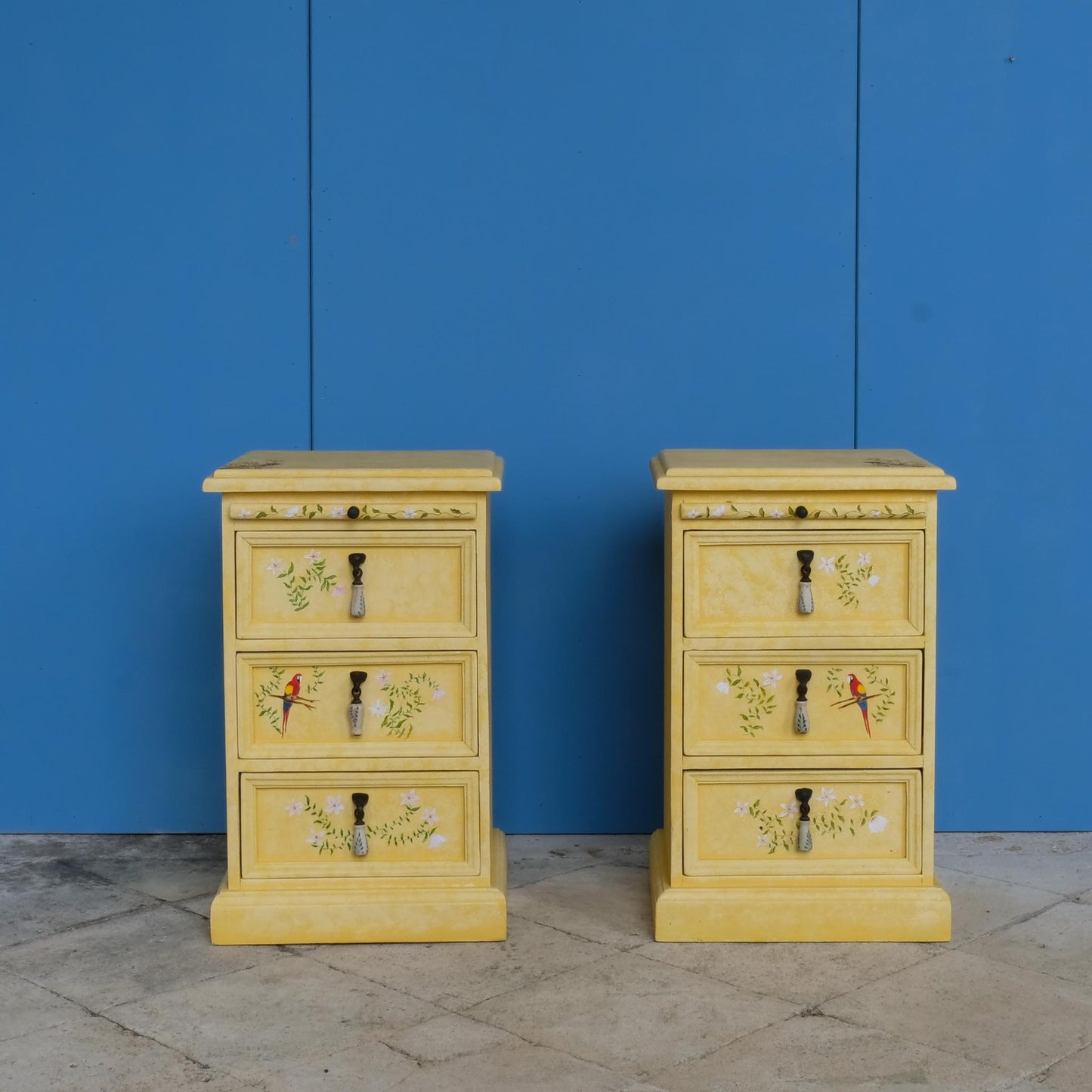 A stunning, unique matching pair of hand-painted chests of drawers, with brushing slides over three drawers. Finished in a fetching patinated yellow and decorated with exotic animals and Flora, in very good condition. Ideal for a children's bedroom or to liven up a sitting room.  A unique pair in collaboration with Bunny Howe.