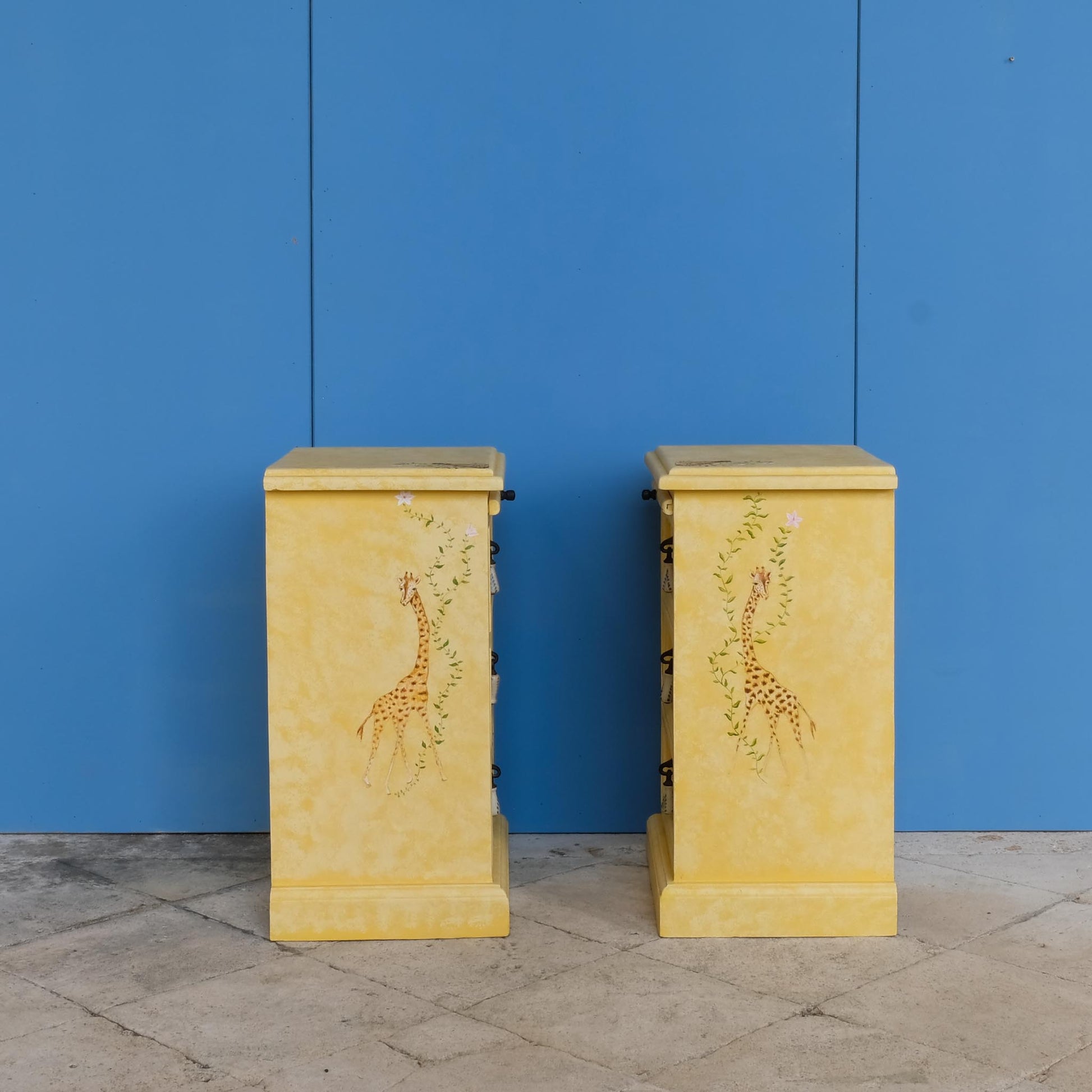 A stunning, unique matching pair of hand-painted chests of drawers, with brushing slides over three drawers. Finished in a fetching patinated yellow and decorated with exotic animals and Flora, in very good condition. Ideal for a children's bedroom or to liven up a sitting room. A unique pair in collaboration with Bunny Howe.