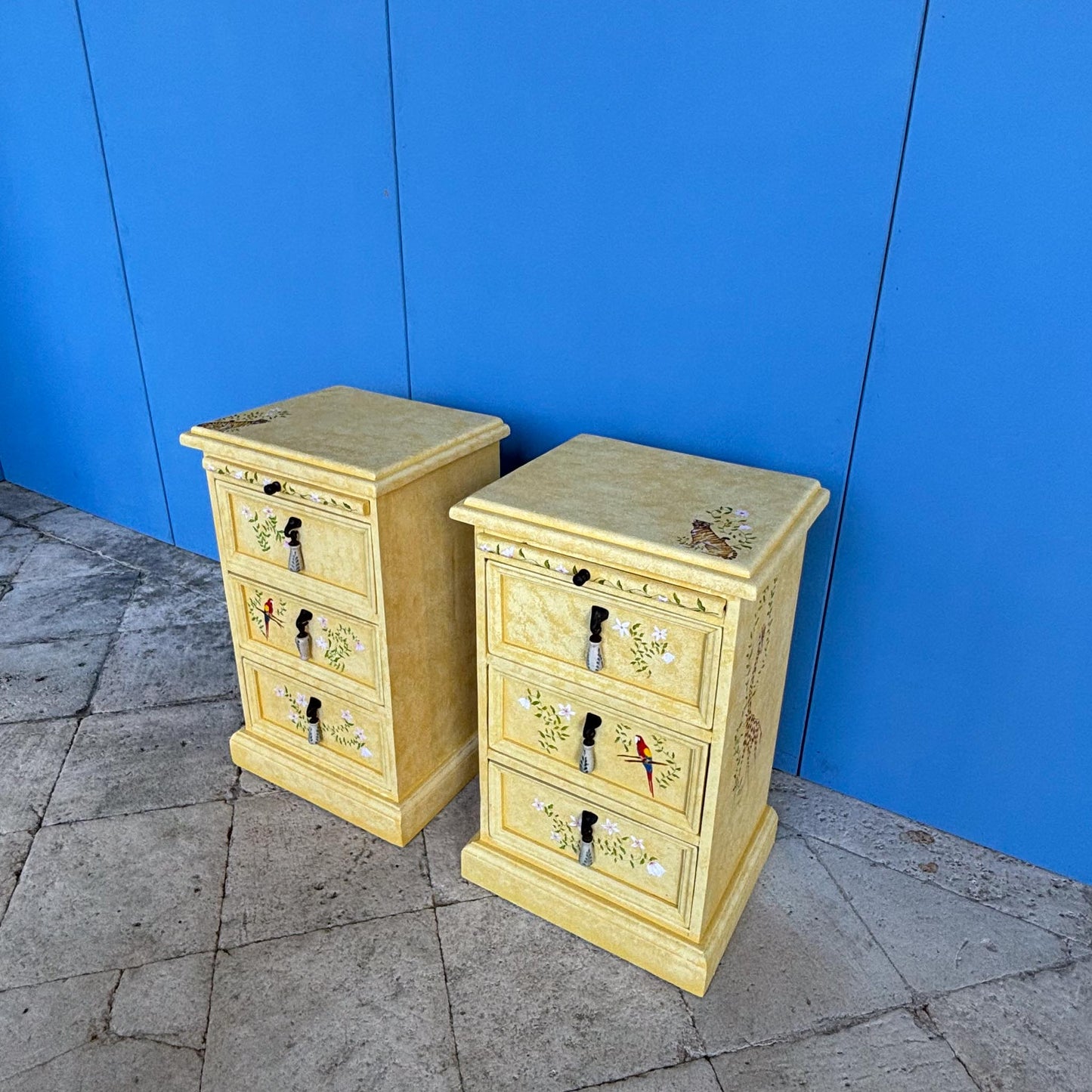 A stunning, unique matching pair of hand-painted chests of drawers, with brushing slides over three drawers. Finished in a fetching patinated yellow and decorated with exotic animals and Flora, in very good condition. Ideal for a children's bedroom or to liven up a sitting room. A unique pair in collaboration with Bunny Howe.